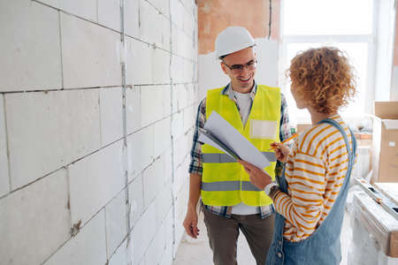 Friendly engineering team discussing the project. Next to a brick wall inside a building under construction.の写真素材