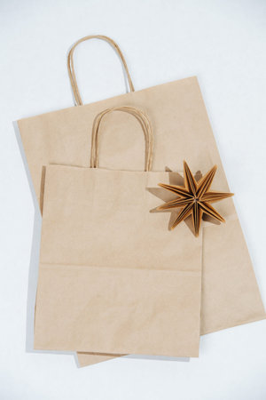 Two flat paper bags with rope handles and origami star on a white surface. Eco friendly compostable...