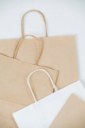 Close up of flat empty brown paper bags on a white surface with rope handles. Eco friendly compostable packaging.の写真素材