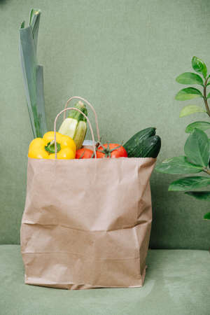 Stuffed paper bag filled with colorful vegetables over green corner. Eco friendly compostable packaging.の写真素材