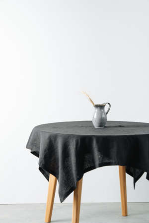 Jug with cereal ear on a round table with a black rough tableclothの写真素材
