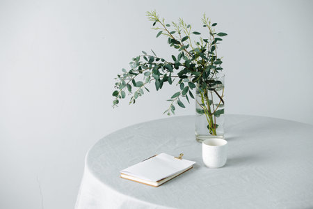 Notepad on a round table with a rough tablecloth and branch in a jarの写真素材