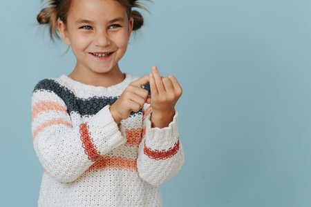 Perky little girl in striped sweater counting on her fingers over blue background. She is smiling at...