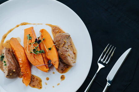 Top view of plated chicken breast with carrot and sauce over black