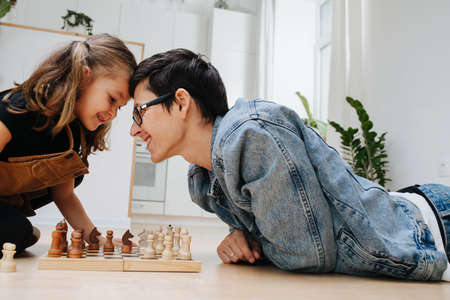 Fun rivalry chess match between dad and his child daughter while batting headsの写真素材