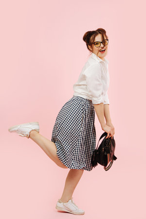 Childish eccentric student lady making girly run pose. Over pink background.