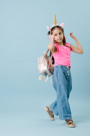 Vibrant tween girl in pink shirt and unicorn hair band speaking on her phone. She has dyed hair...