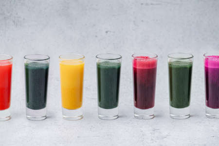 Colorful home made detox drinks from dissolved powder in a row on the table. Green, orange, red and purple.の写真素材