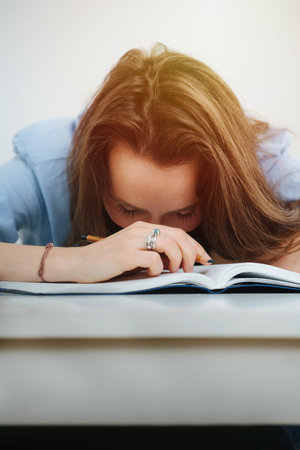 Napping business woman in blue dress shirt fell asleep while writing in a journal. Lying on a desk.