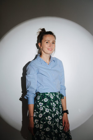 Cinematic portrait of a charming 30 year old woman looking at camera. In a circle of light. She has...