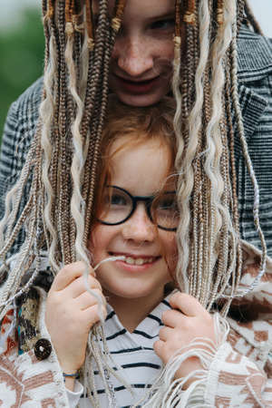 Loving sister putting her dreads over cute cute girl's. She is smiling, looking at the camera. Wearing glasses.の写真素材