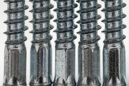 Screws with hexagonal shaft in a row of five. close up. Gray color of stainless steel.