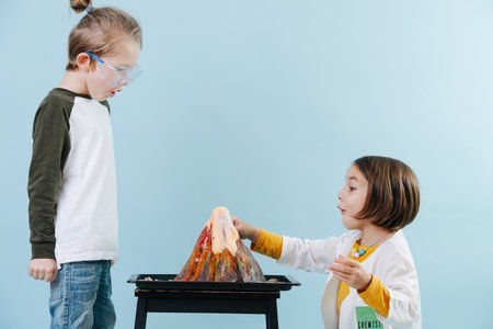 Astonished kids doing chemical volcano experiment, looking at it erupting with gaping mouths.の写真素材