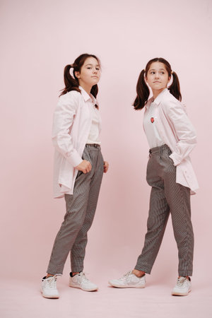 Fashionable twin girls with dress shirt over T shirt. Wearing pigtails and black and white patterned...