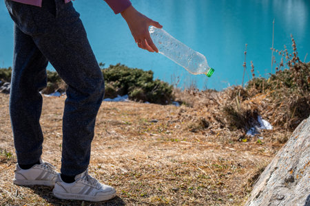 Cropped image of a woman picking up trash in a natural reserve. Lower part of a body, comfortable...