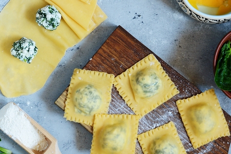 Cooking Raviolli homemade pasta with ricotta and spinach on a blue backgroundの写真素材