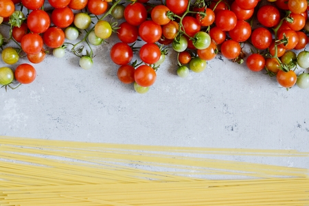 Food frame. Pasta ingredients concept. Uncooked spaghetti and cherry on a blue background. Top view with copy space. Italian foodの写真素材