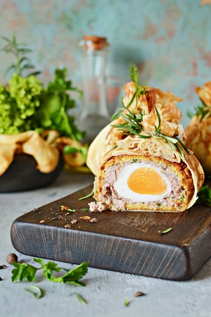 Scotch eggs in green pancake bag with greens on a gray-blue background. A classic dish in an unconventional serving. Delicious and appetizing dish of British cuisine.の写真素材
