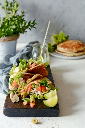 Unsweetened pancakes with turkey, lettuce, tomatoes and pickles tasty snack of their pancakes and vegetables. Healthy eating conceptの写真素材