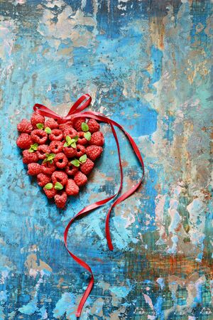 Heart shape made of premium raspberries on a blue background. Close up, top view, high resolution product. Romantic concept. Valentine's day symbolの写真素材