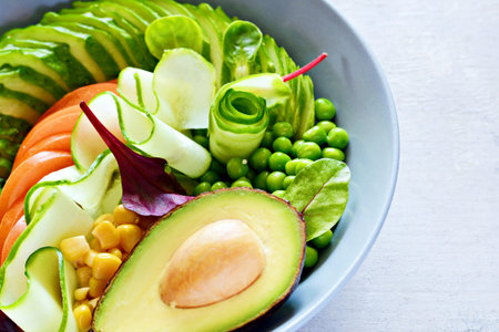 Healthy vegetarian food. Fresh vegetables cucumber, tomato, corn, green peas, avocado, lettuce in a...