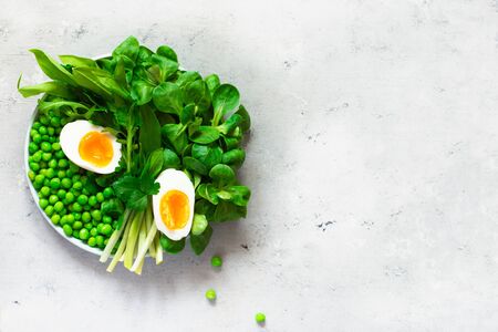Soft-boiled eggs with lettuce, wild garlic, green peas and parsley. Healthy eating concept. Go veganの写真素材
