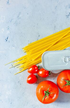 A set of products for the preparation of pasta, spaghetti, tomatoes, canned food (tuna). Food donation on a blue background. Food collection during a pandemic (epidemic), safe food delivery.の写真素材