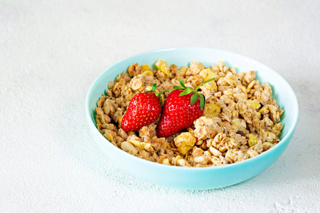 Homemade crunchy granola with nuts, dried fruits, fresh strawberries, on a plate. Healthy breakfast...