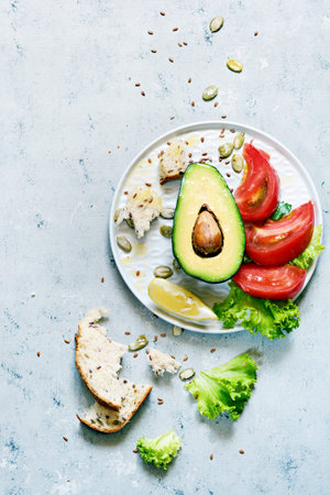 Healthy food. Half a ripe avocado with seed and lettuce on a plate on a gray background. Avocado salad Flat lay. Food concept. Top view.の写真素材