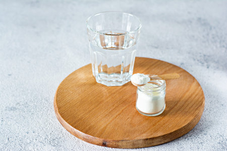 Collagen powder with a glass of water on a light background. Extra protein intake. Natural beauty...