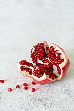 Ripe Broken Pomegranate with bright juicy large grains (seeds) on a gray background, Copy spaceの写真素材
