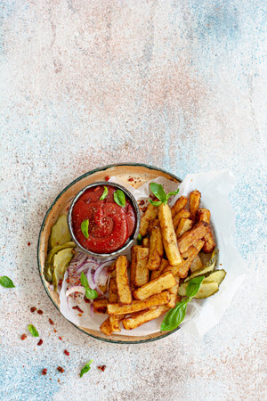 Fried potatoes (deep fried) with herbs and spices, ketchup, pickles and slices of pickled onion on a...
