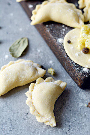 Dumplings with potatoes with herbs on a blue background. Varenyky, vareniki, pierogi, pyrohy -...
