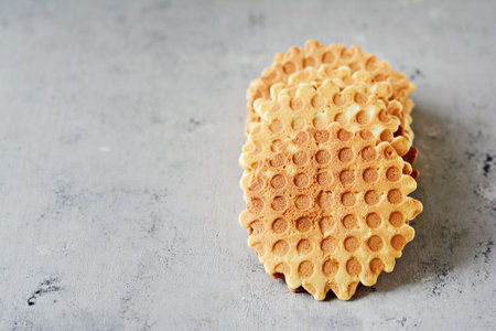 A stack of Dutch (Belgian) waffles with salted caramel on a gray background. Sweet waffle dessert.