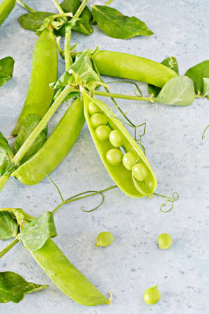 Pods of fresh green peas on a blue background, healthy vegetables.の写真素材