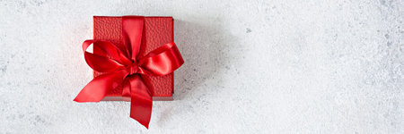 Banner with a red gift box with a red satin ribbon (bow) on a light background. Congratulatory...
