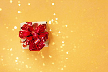 Many gift boxes with a bright shiny red bow, sparkles and glitter on a bright orange (yellow) background. Present for birthday, christmas, new year. Festive concept.の写真素材