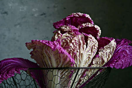 A swing of fresh purple Chinese (Peking) cabbage in a basket on a dark wooden background. Healthy eating concept, go vegan.の写真素材