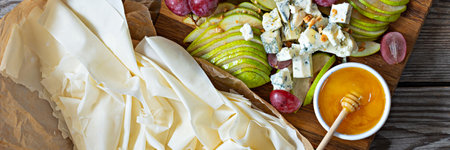 Ingredients for making a phyllo dough tart, fruits (grapes, pears), cheese and nuts with honey. Cooking mediterranean cuisine.の写真素材