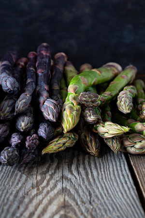 Raw purple, green asparagus on a dark wooden background. Raw food concept, place for copy space.の写真素材