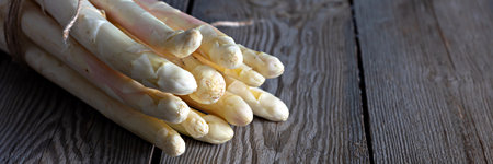 Fresh white asparagus on a wooden background. Photo in low key. Raw food concept.の写真素材