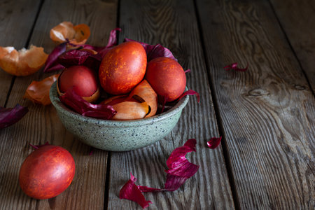 Boiled eggs dyed with onion peel in a bowl on a wooden background. Traditional Easter concept.の写真素材