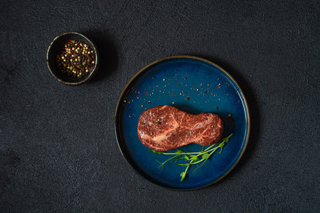 Raw marbled beef steak on plate ready to cook with microgreens. The shape of the steak is light bulb. Food energy concept for human, top view, minimalism.の写真素材