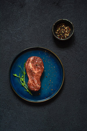 Raw marbled beef steak on plate ready to cook with microgreens. The shape of the steak is light bulb. Food energy concept for human, top view, minimalism.の写真素材