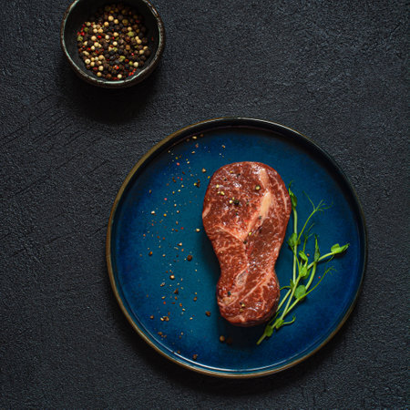 Raw marbled beef steak on plate ready to cook with microgreens. The shape of the steak is light bulb. Food energy concept for human, top view, minimalism.の写真素材