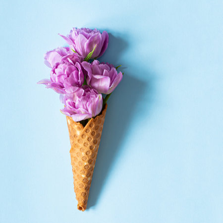 Wafer cone with tulips on a blue background. Flower ice cream, spring concept with first flowers.の写真素材
