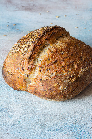 Fresh whole grain sourdough bread with flax seeds, oatmeal, sesame seeds on colored background, healthy food concept unleavened bread.の写真素材