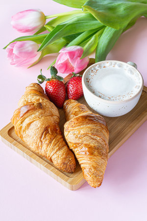 Happy mother's day, Valentine's Day beautiful breakfast, lunch with cup of coffee (cappuccino) fresh croissants, strawberries on tray, bouquet of tulips as gift. Festive concept. Spring holiday, family relations.の写真素材