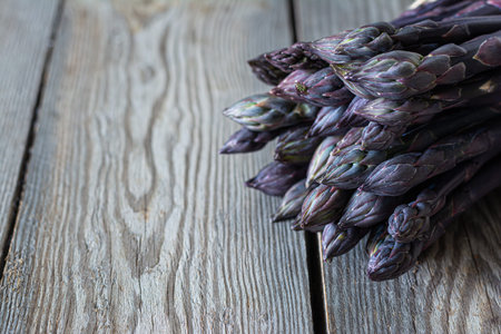 Fresh bunch of purple asparagus on dark wooden background. Healthy food concept. The vegetable is rich in fiber, a natural prebiotic.の写真素材