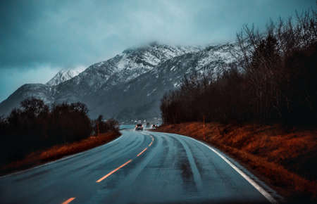 Road trip to Norway, driving on highway along beautiful high snowy mountains, traveling to Europe, freedom and adventure concept..